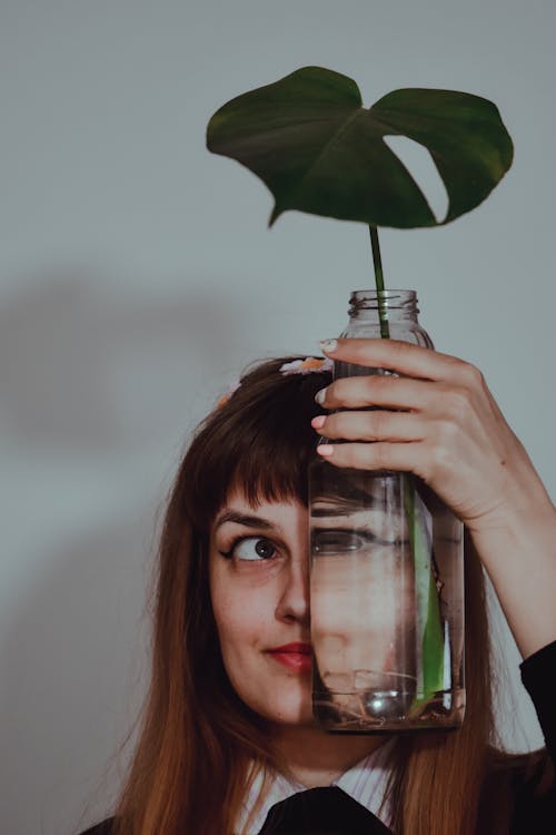 
A Woman Holding a Glass Bottle with a Plant