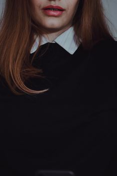 Close-up portrait of woman with red lips and long brown hair, dressed in black.