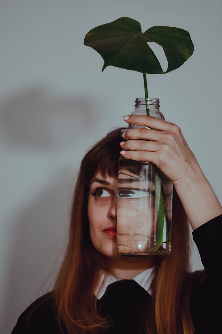 A Funny Woman Holding Glass Vase On Her Face