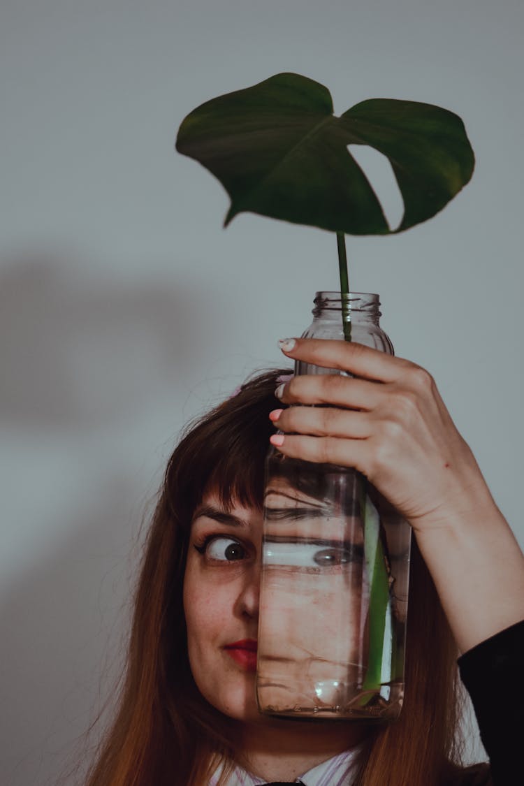 A Funny Woman Holding Clear Glass Jar On Her Face