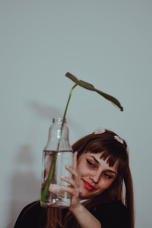 A Woman Holding Clear Glass Bottle with Leaf