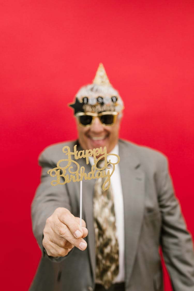 A Man Holding Birthday Greeting On Stick