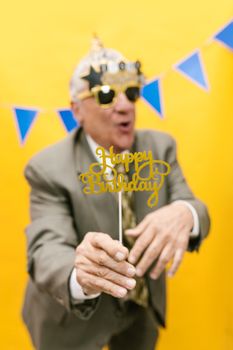 Senior man in suit joyfully celebrating birthday with decor.