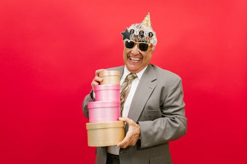 A Man in Gray Suit Holding a Pile of Gift Boxes