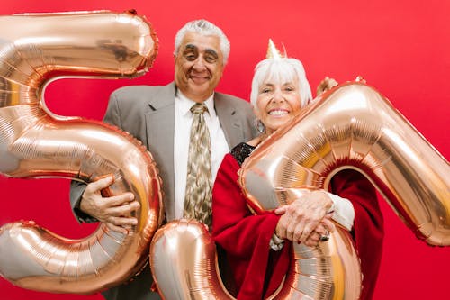 Elderly Man and Elderly Woman Holding Number Balloons