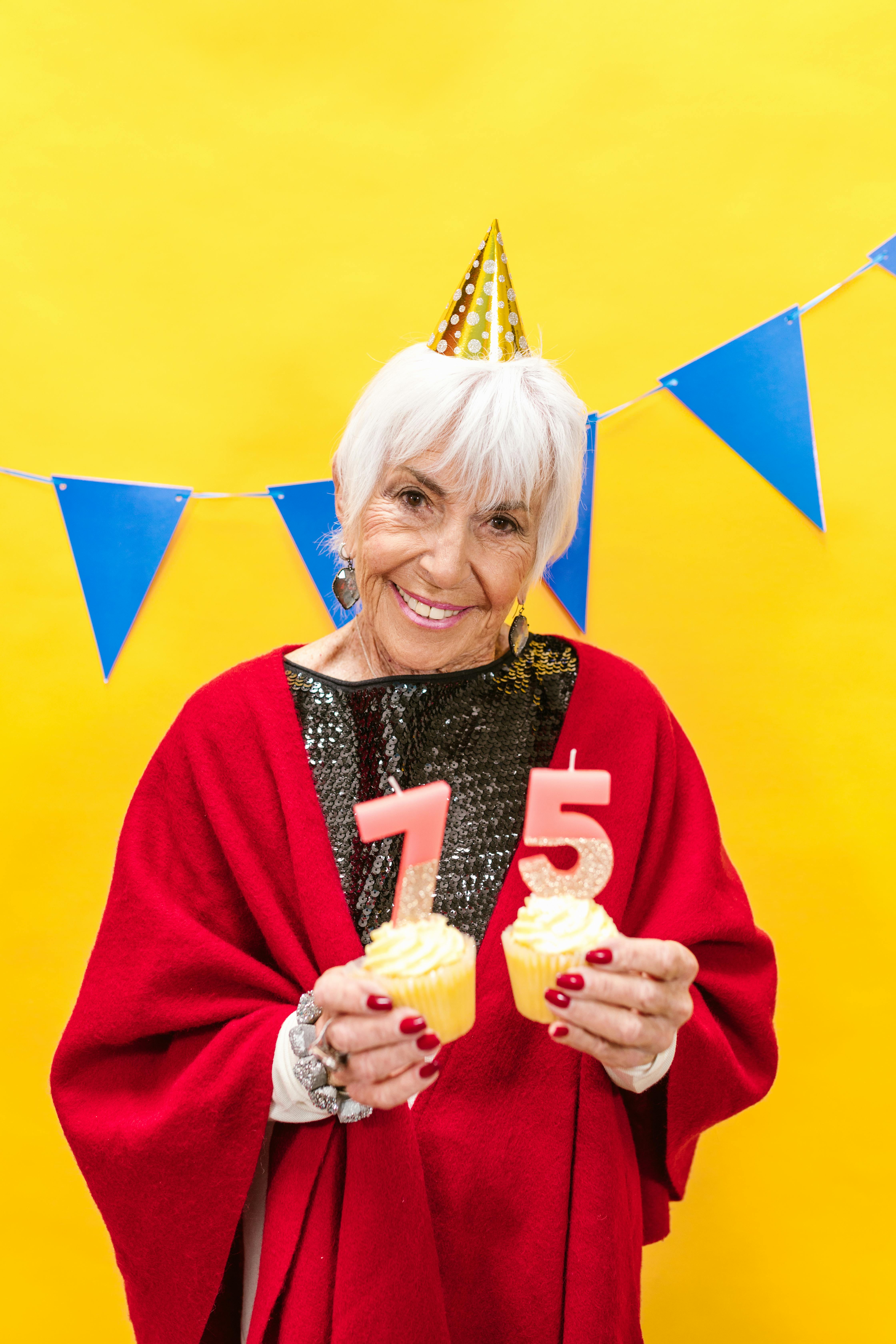 woman with party hat holding cupcakes