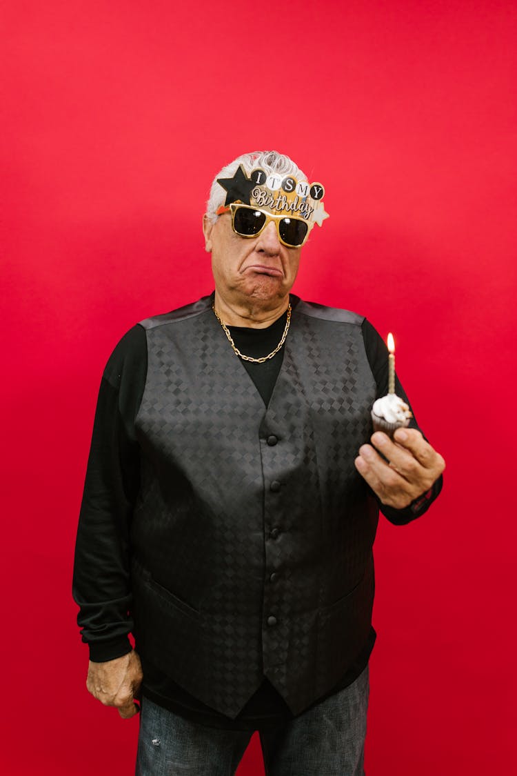 An Elderly Man Holding A Cupcake