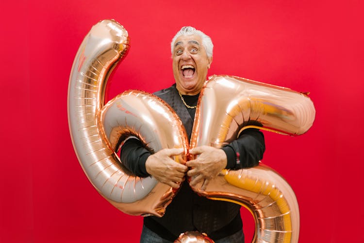 Man Holding Gold Balloons In Red Background 