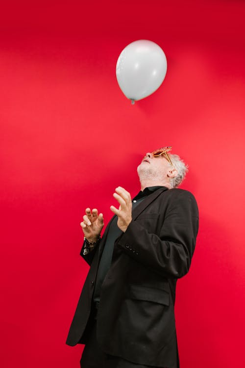 Man in Black Suit Jacket Looking at a Balloon