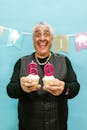 Gray Haired Man Holding Cupcakes with Numbers