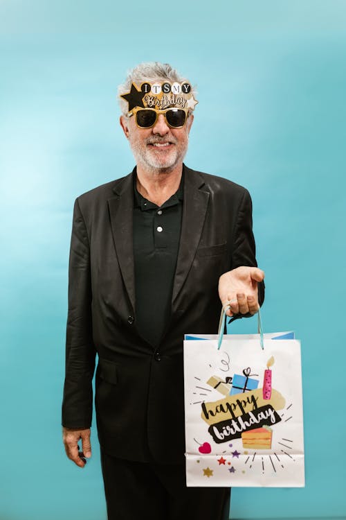 Free Elderly Man in Black Suit With Sunglasses Holding a Paper Bag  Stock Photo
