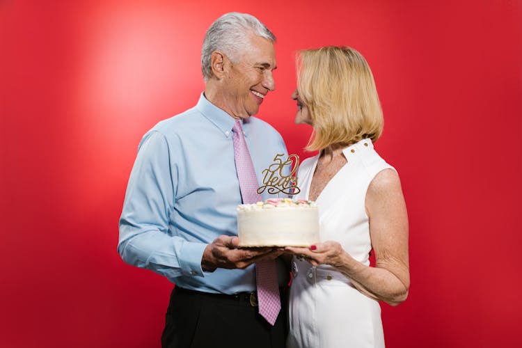 A Happy Elderly Couple Holding A Cake