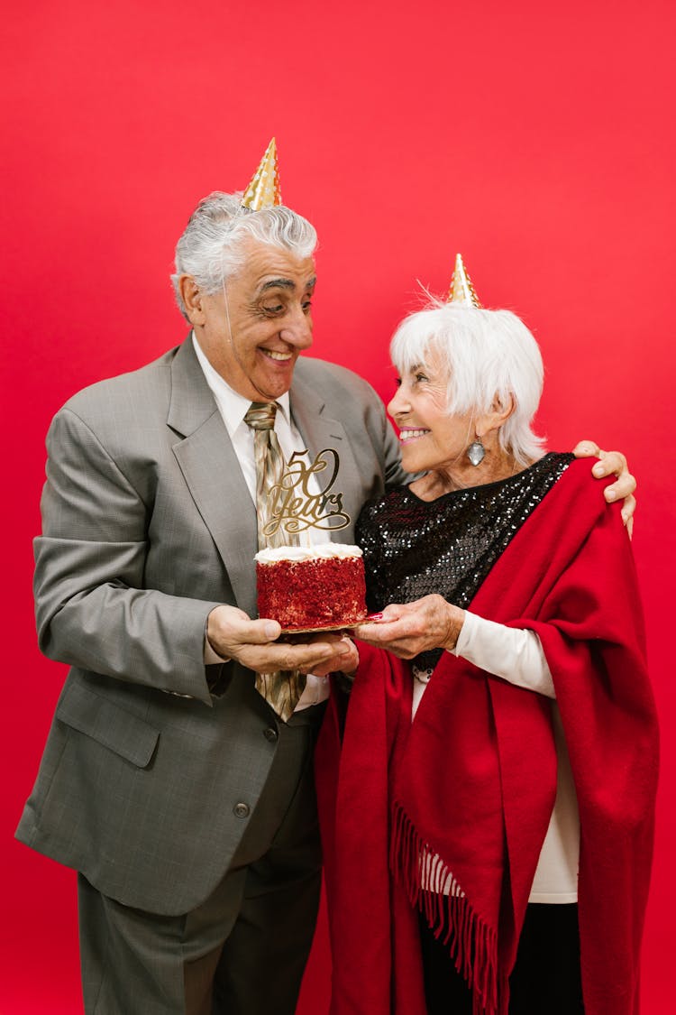 A Happy Elderly Couple Holding A Cake