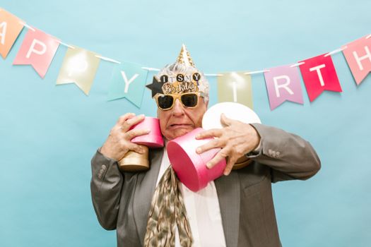 Elderly man joyfully celebrating his birthday with gifts and decorations.