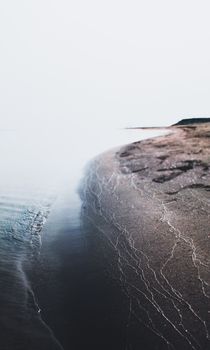 A tranquil view of a foggy coast with waves lapping at the sandy beach, Chilmari, Bangladesh.