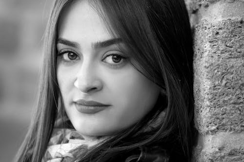 Monochrome Photography of a Woman Leaning Against the Wall