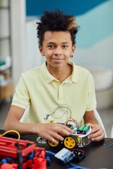 A young boy learns about robotics indoors, focusing on assembling electronic components.