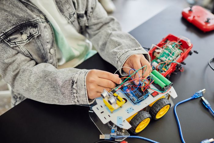 Student assembling a robotic car with electronic components