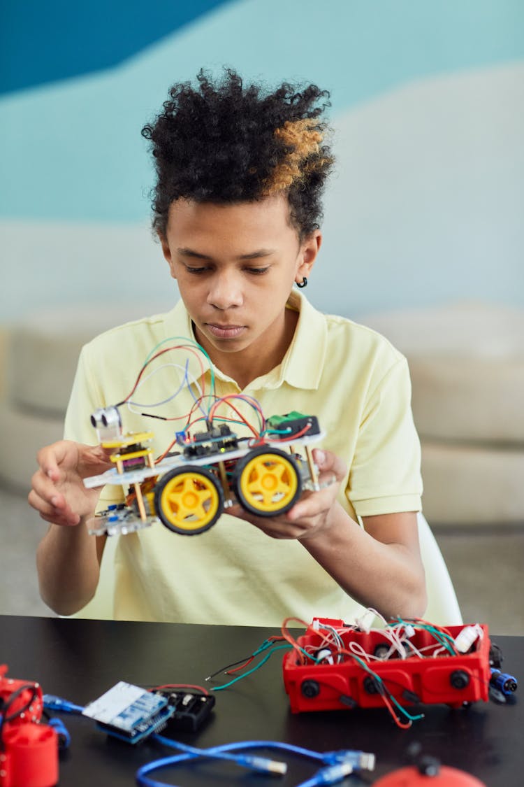 A Young Boy Holding A Robotic Car