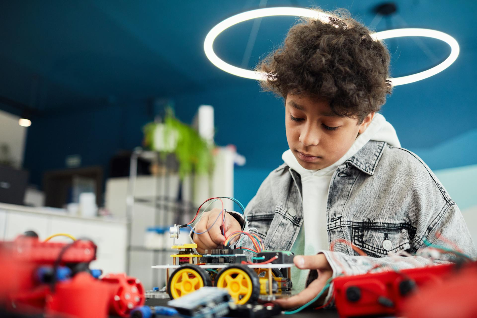 A focused young boy works on a robotics project indoors, showcasing learning and innovation.