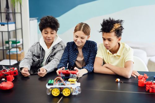 Free Teens exploring and building robotics at a table indoors, showcasing teamwork and technology skills. Stock Photo
