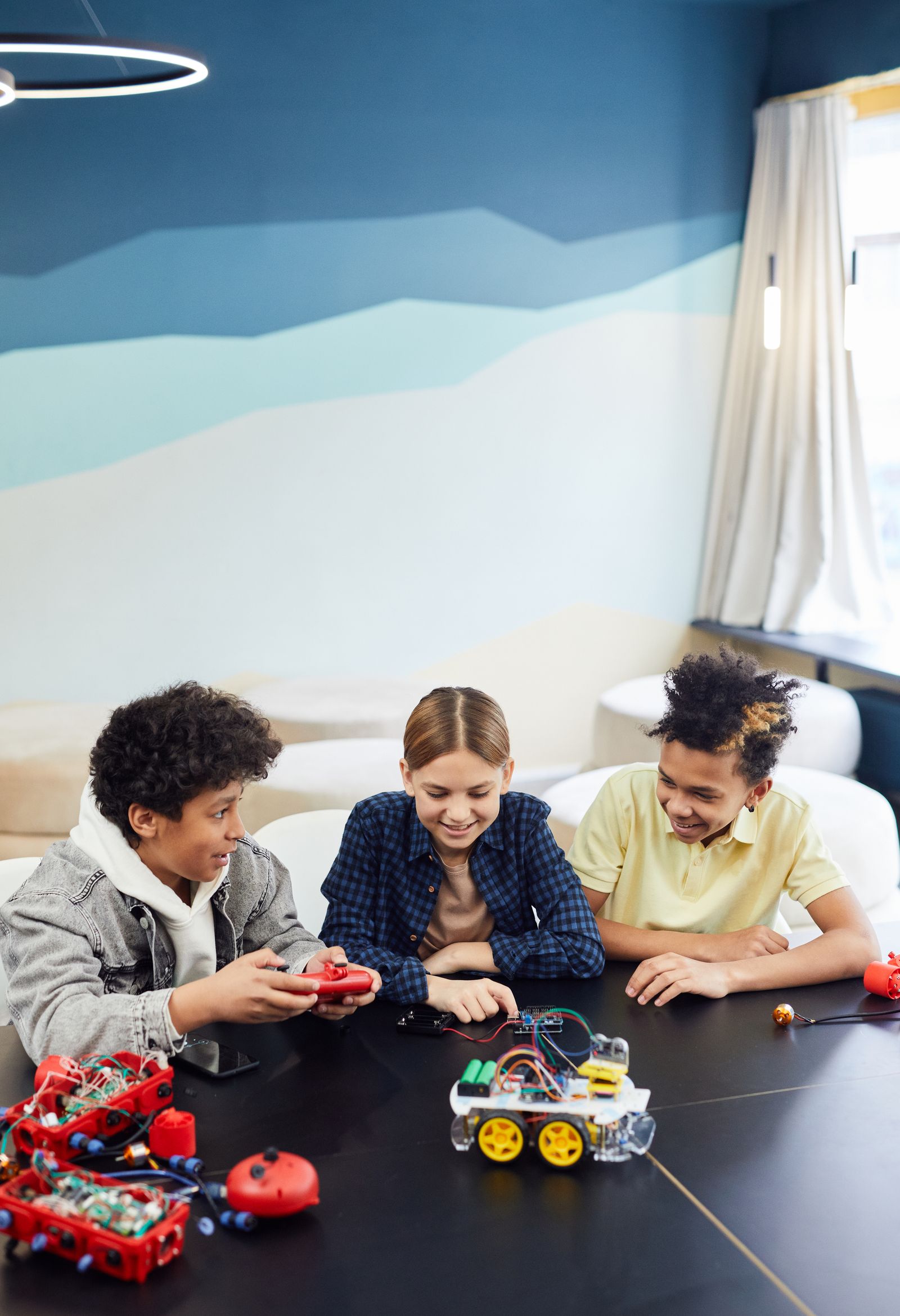 Children exploring robotic toy cars and electronic building kits together
