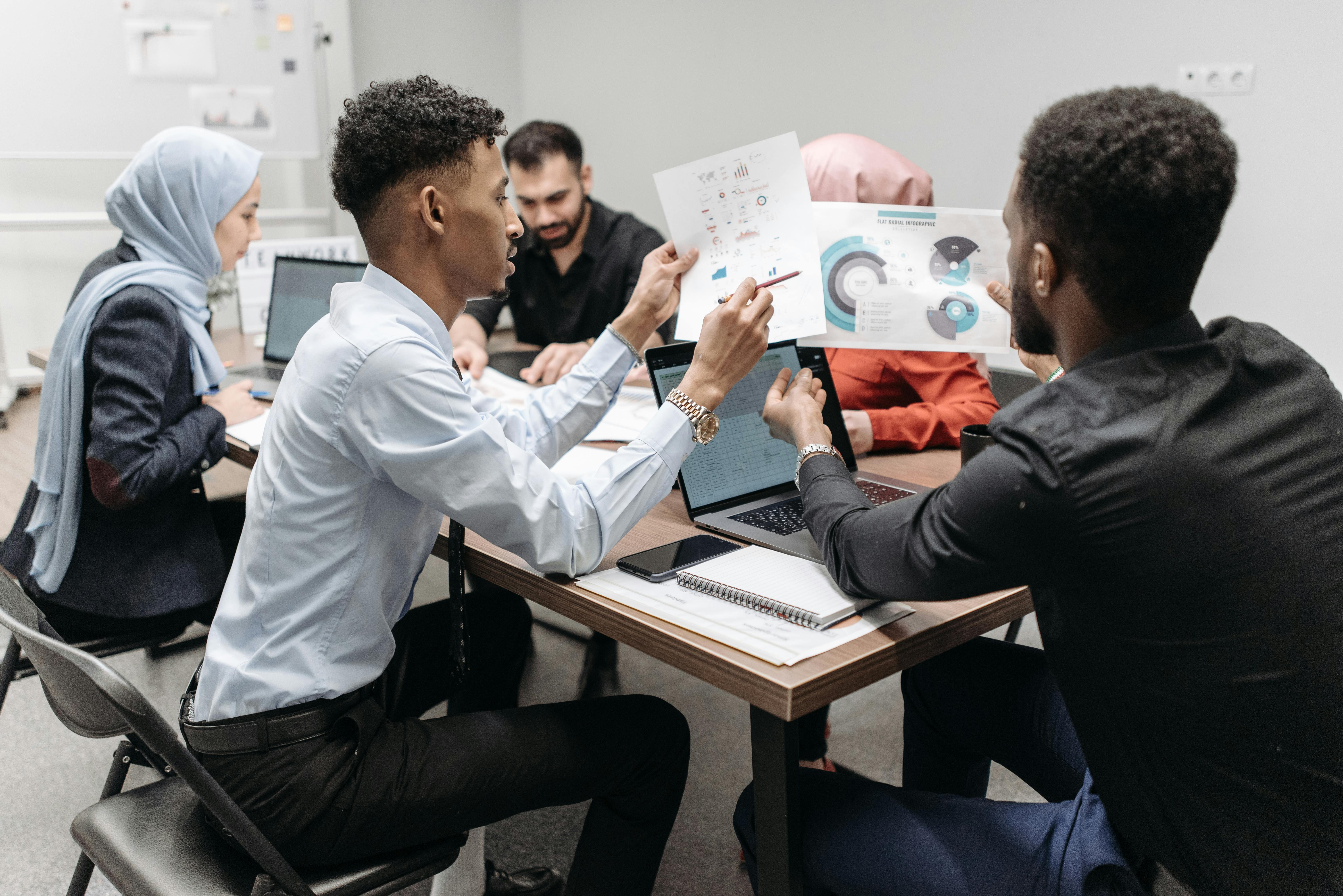 A diverse team of professionals discussing data charts in a modern office. Teamwork and collaboration.