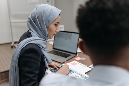 Free Woman in Gray Hijab Sitting Behind an Office Table Stock Photo