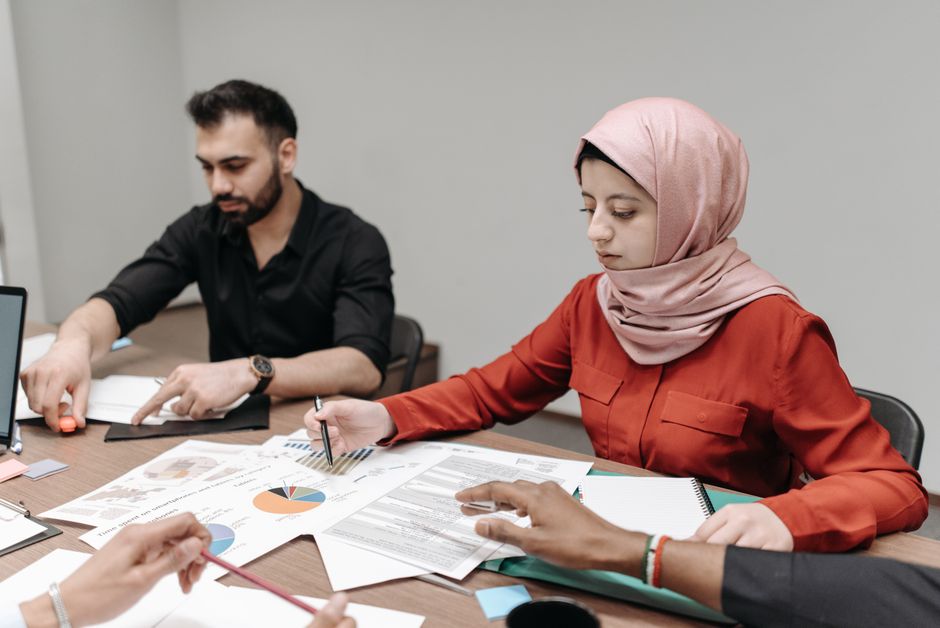 Un grupo de oficina multicultural analizando documentos y gráficos durante una reunión colaborativa.