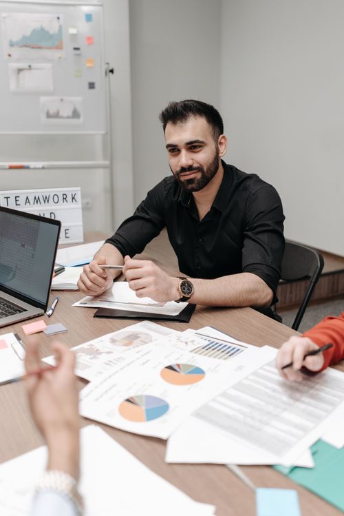 Free Bearded man in black shirt reviewing paperwork at office table during a meeting. Stock Photo
