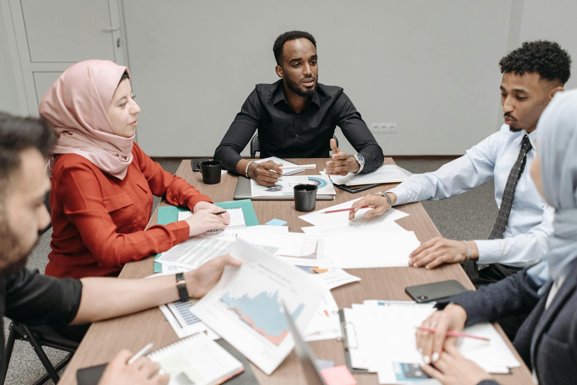 Multicultural team discussing business reports around a table indoors.