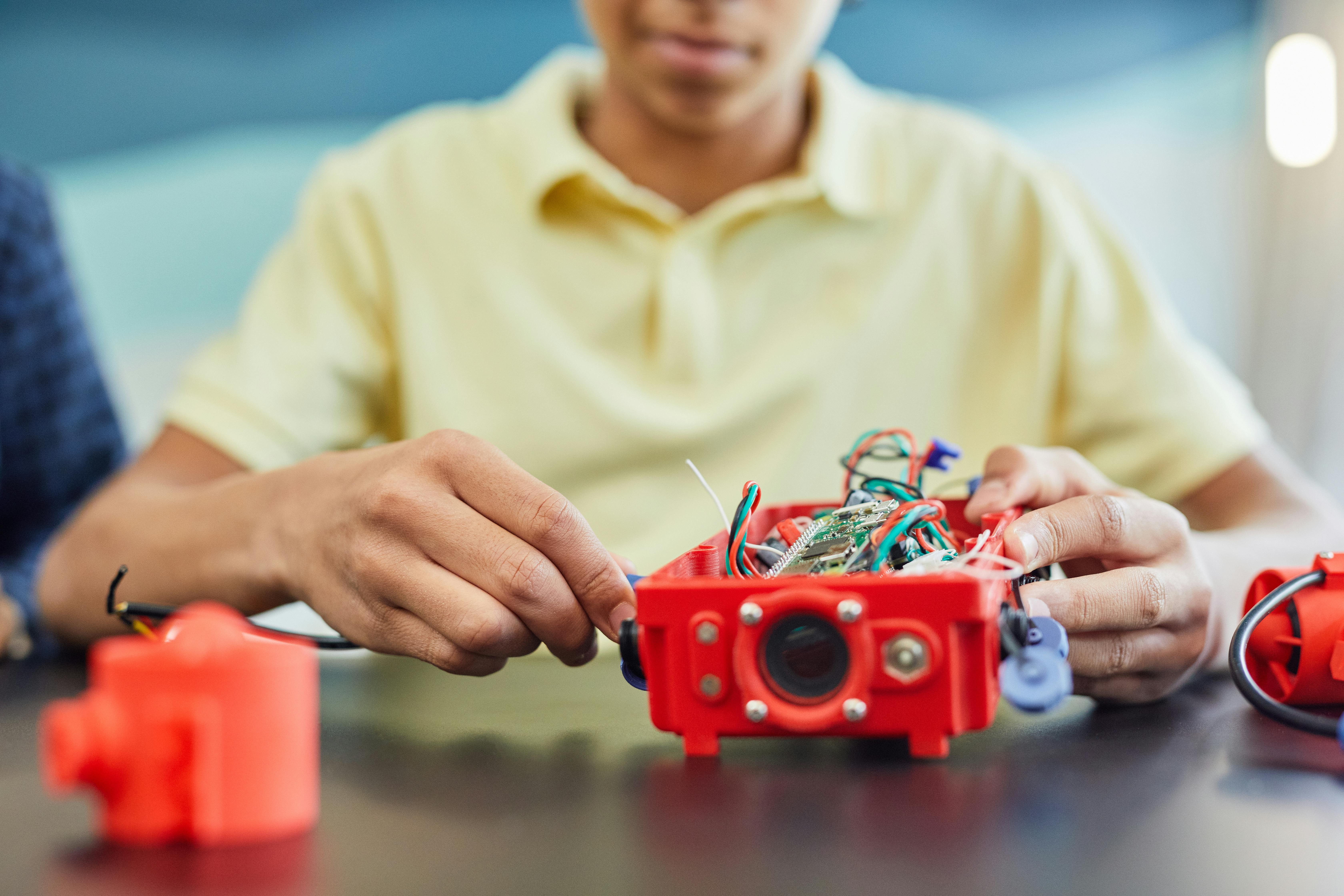 A teenager works on assembling a robotic project, showcasing innovation and creativity.