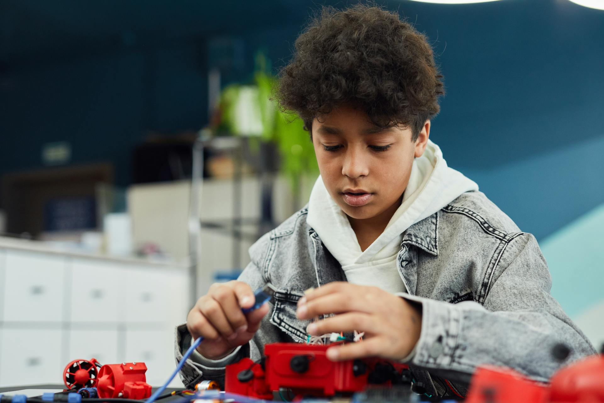 Focused boy working on a robotics project indoors, showcasing learning and creativity.