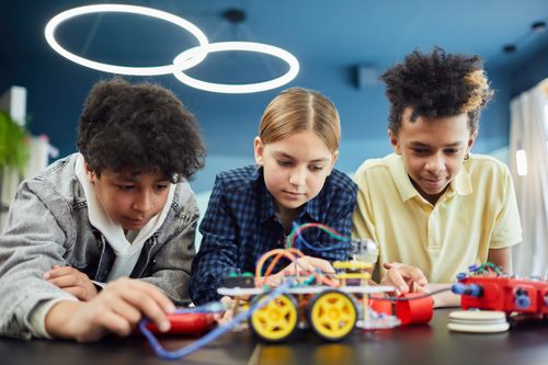 Free Young students focus on building a robotics project together, showcasing teamwork and creativity. Stock Photo
