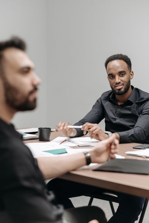 Free Two professionals engaged in a brainstorming session at a modern office desk. Stock Photo
