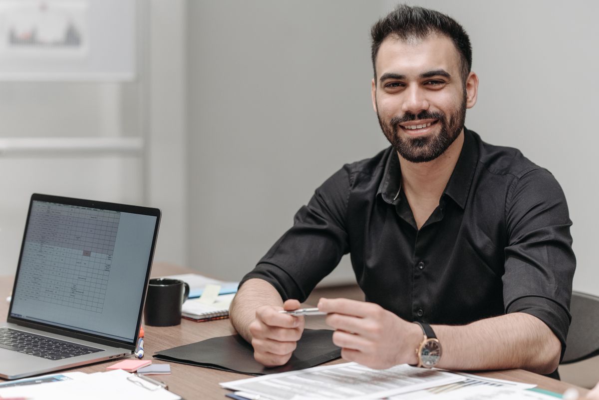 تأهيل العملاء المحتملين من اللحظة الأولى رجل أعمال يجلس إلى مكتبه بجانب حاسوبه ومستنداته