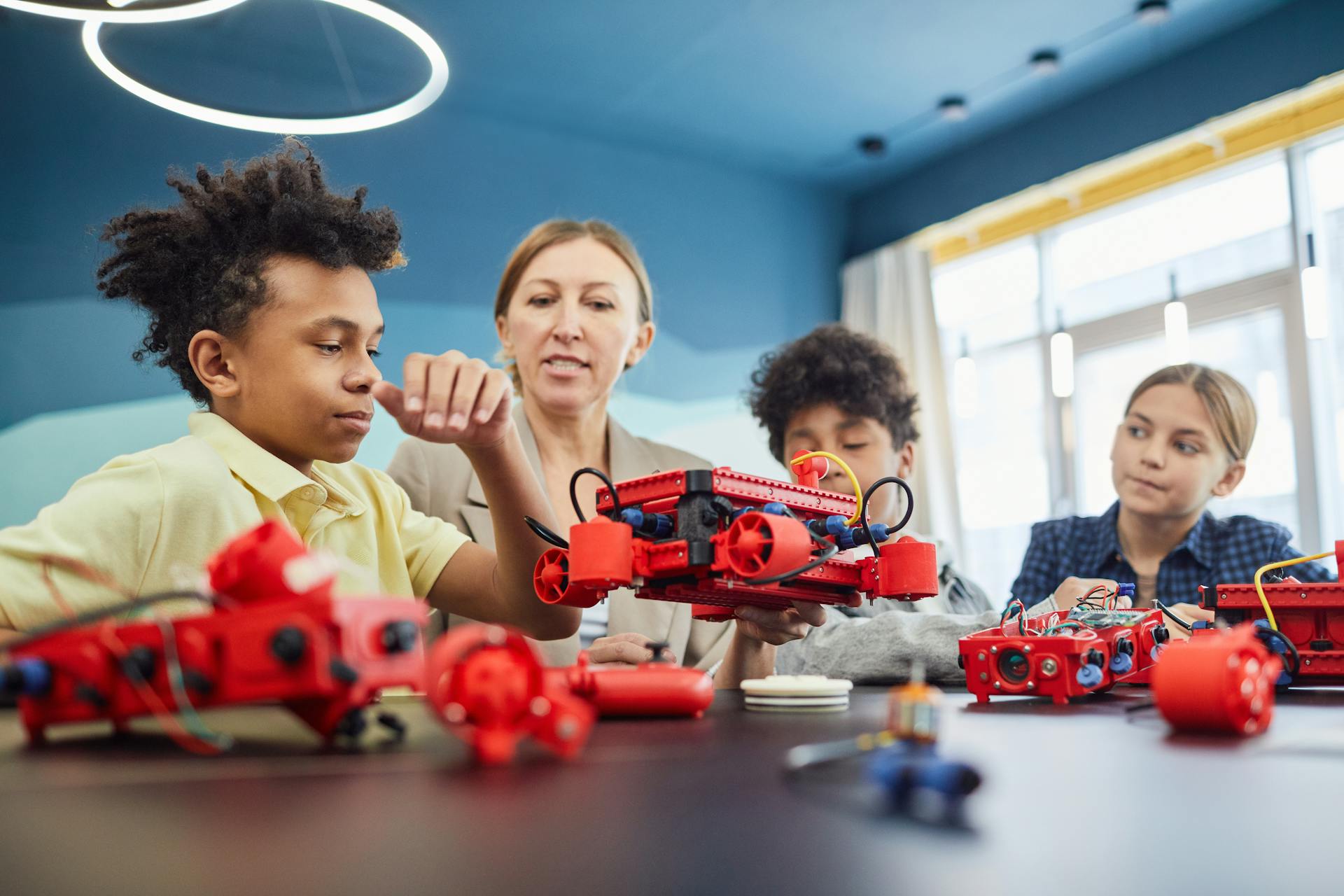 Young students and teacher collaborating on a robotics project in a classroom setting.