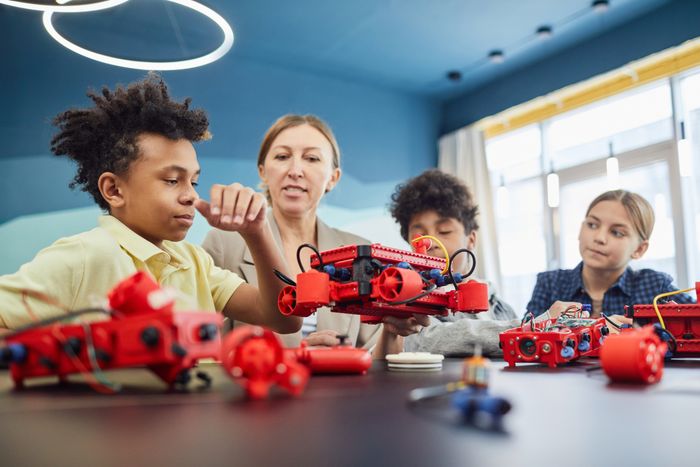 Children building a robot together with their teacher