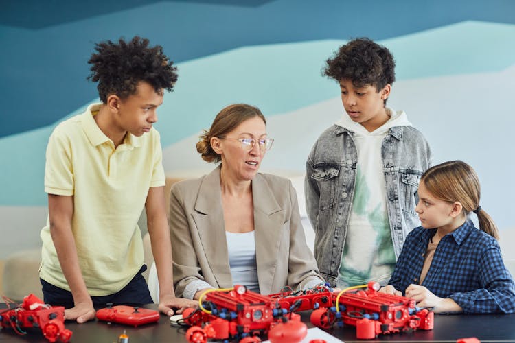 A Woman Discussing Robotics To Young Boys And A Girl