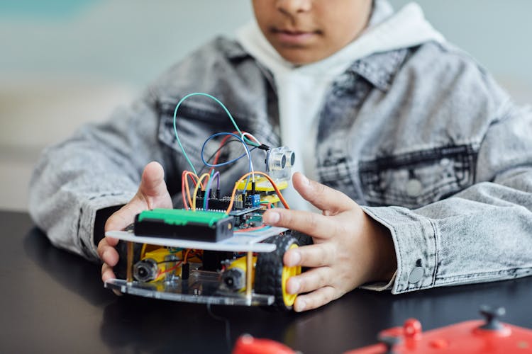 Boy In Denim Jacket Holding A Toy With Electric Wires And Wheel