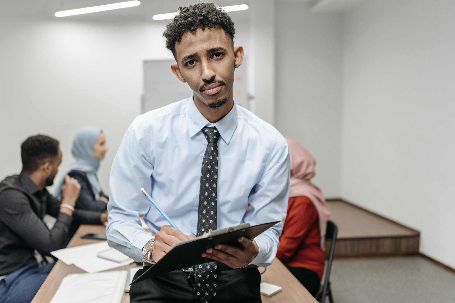 Confident young man leading a team discussion in a modern office setting.