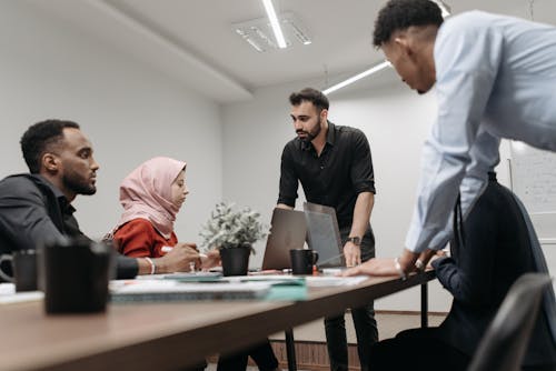 A Man in Black Shirt Discussing With Employees in a Meeting Room