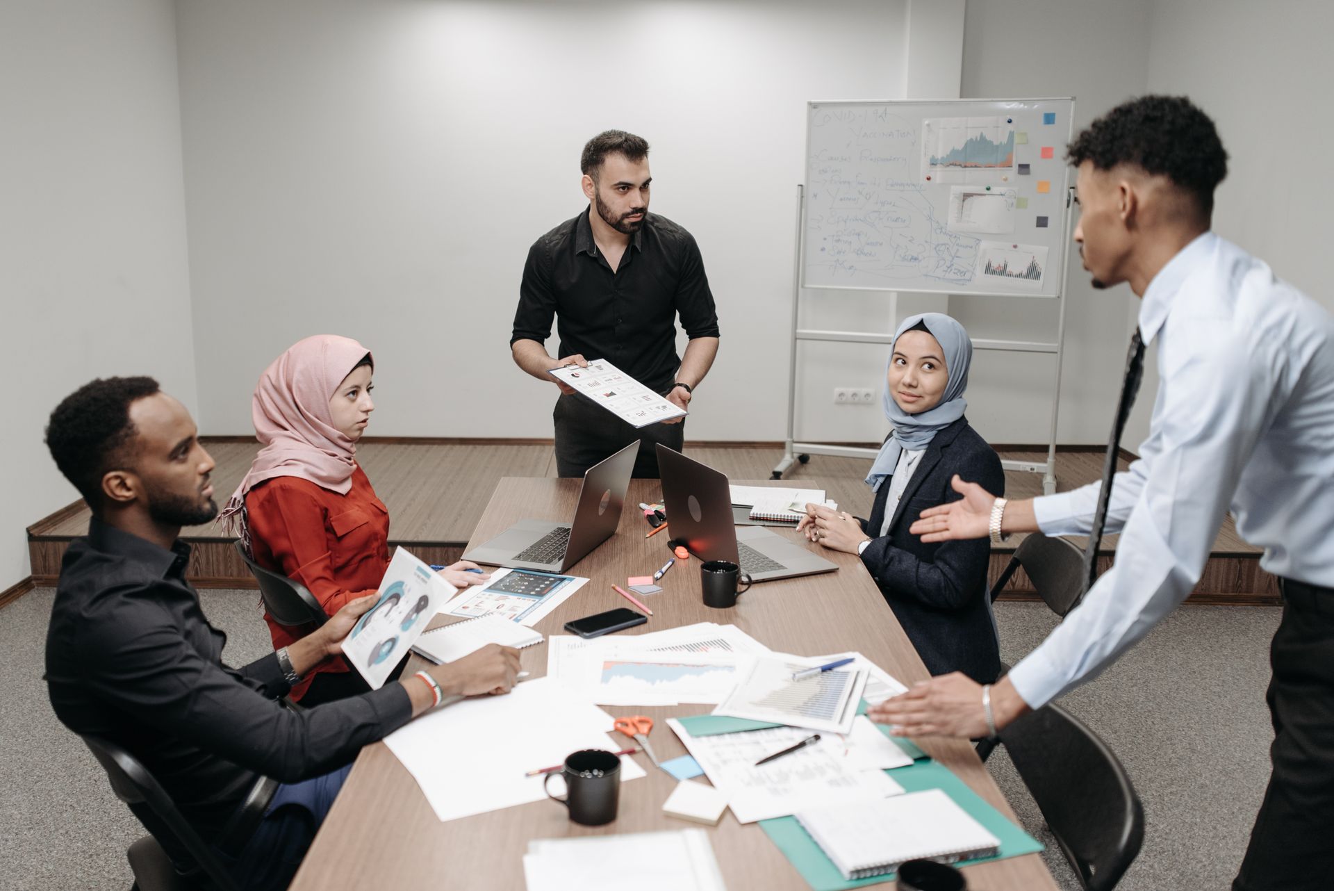 A diverse office team engaged in a collaborative meeting around a table, discussing business strategies.