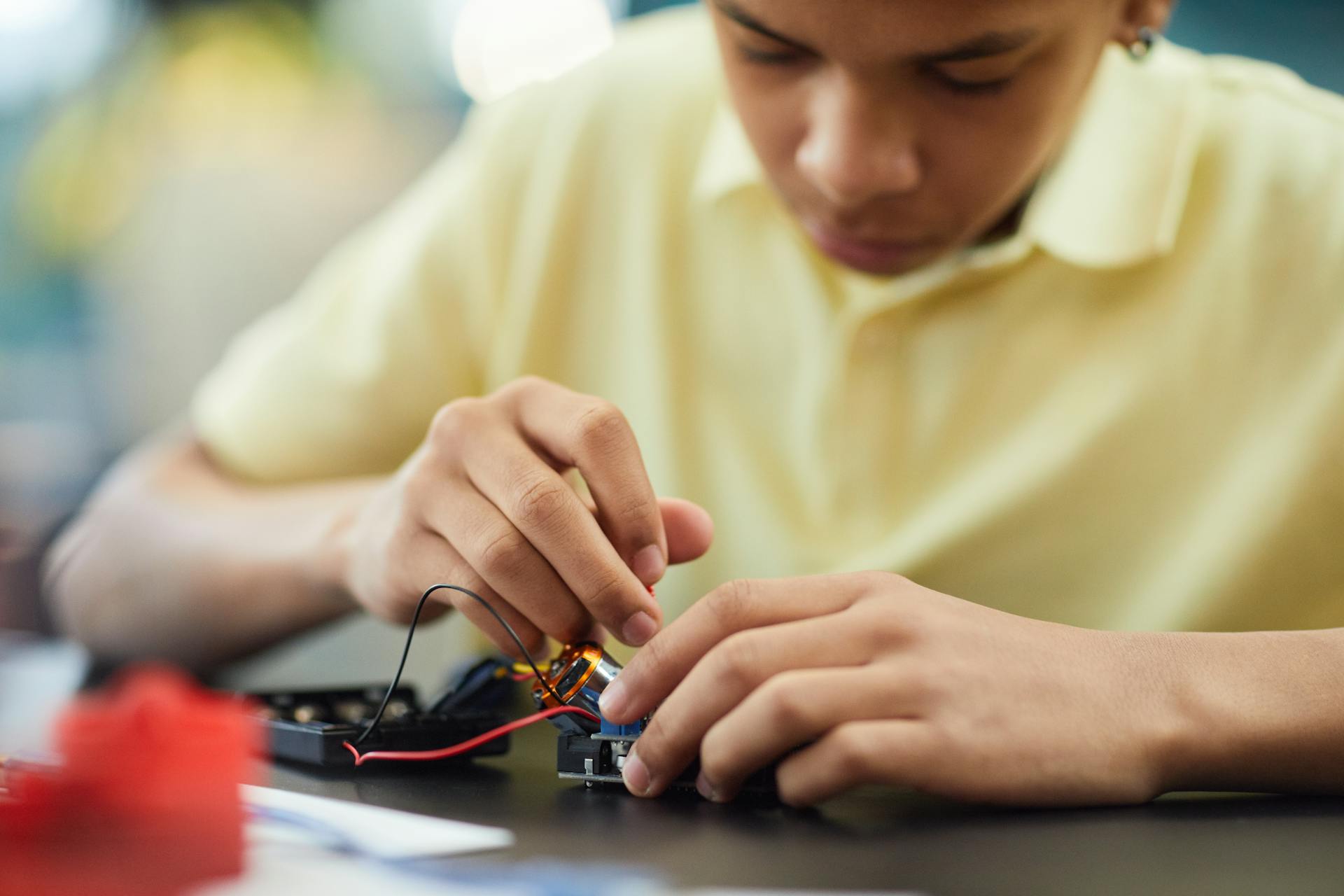 Close-up of a teenager building a robotics project, focusing on electronics and repairs.