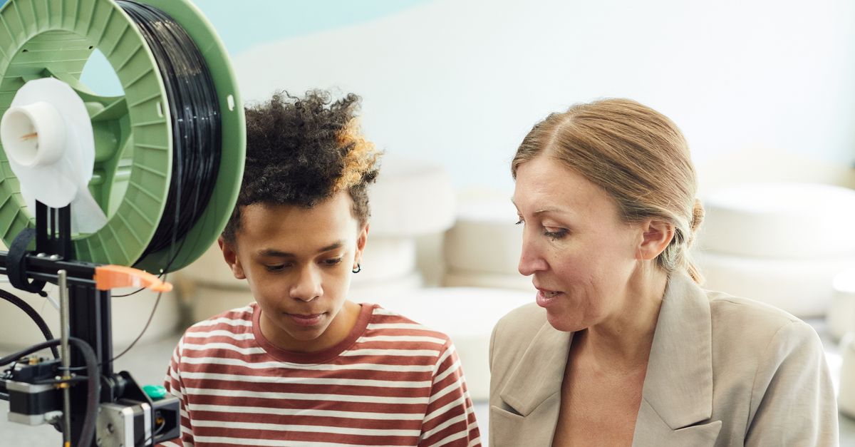Focused woman working with a child on a project near a 3D printer