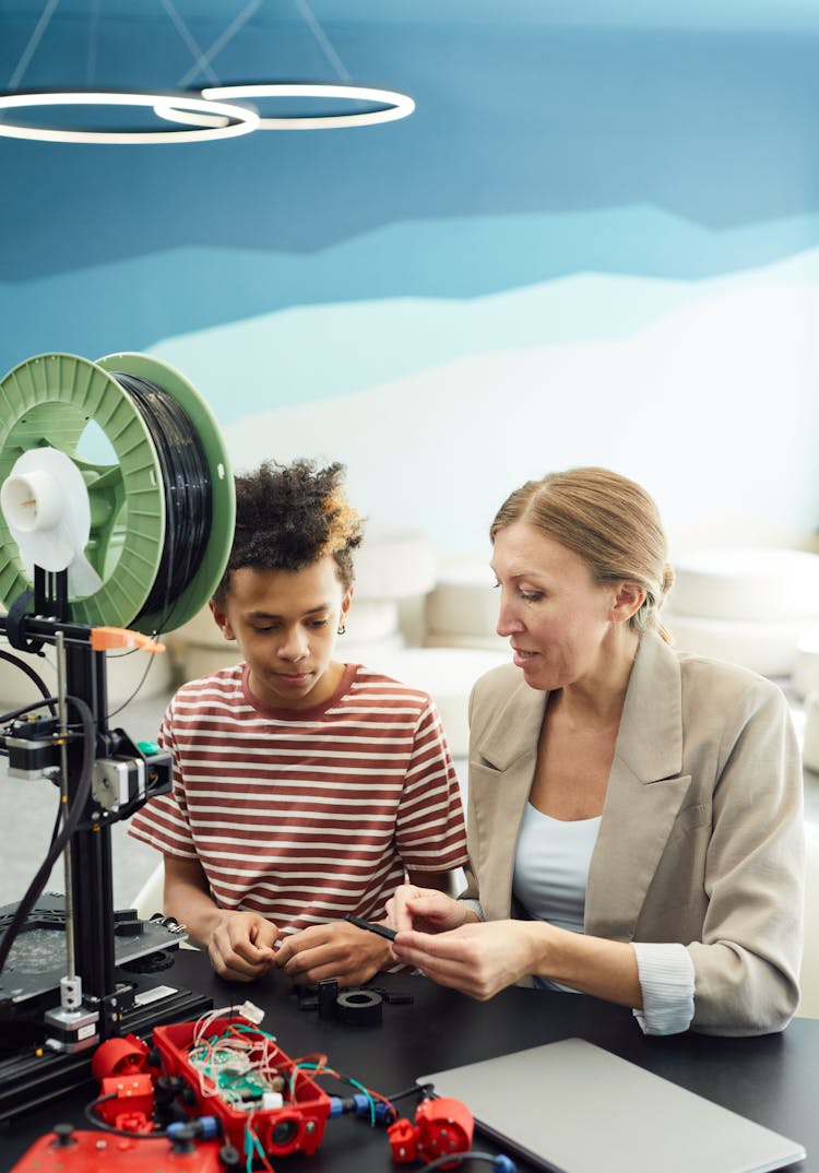 Focused Woman Working With Ethnic Kid On Project