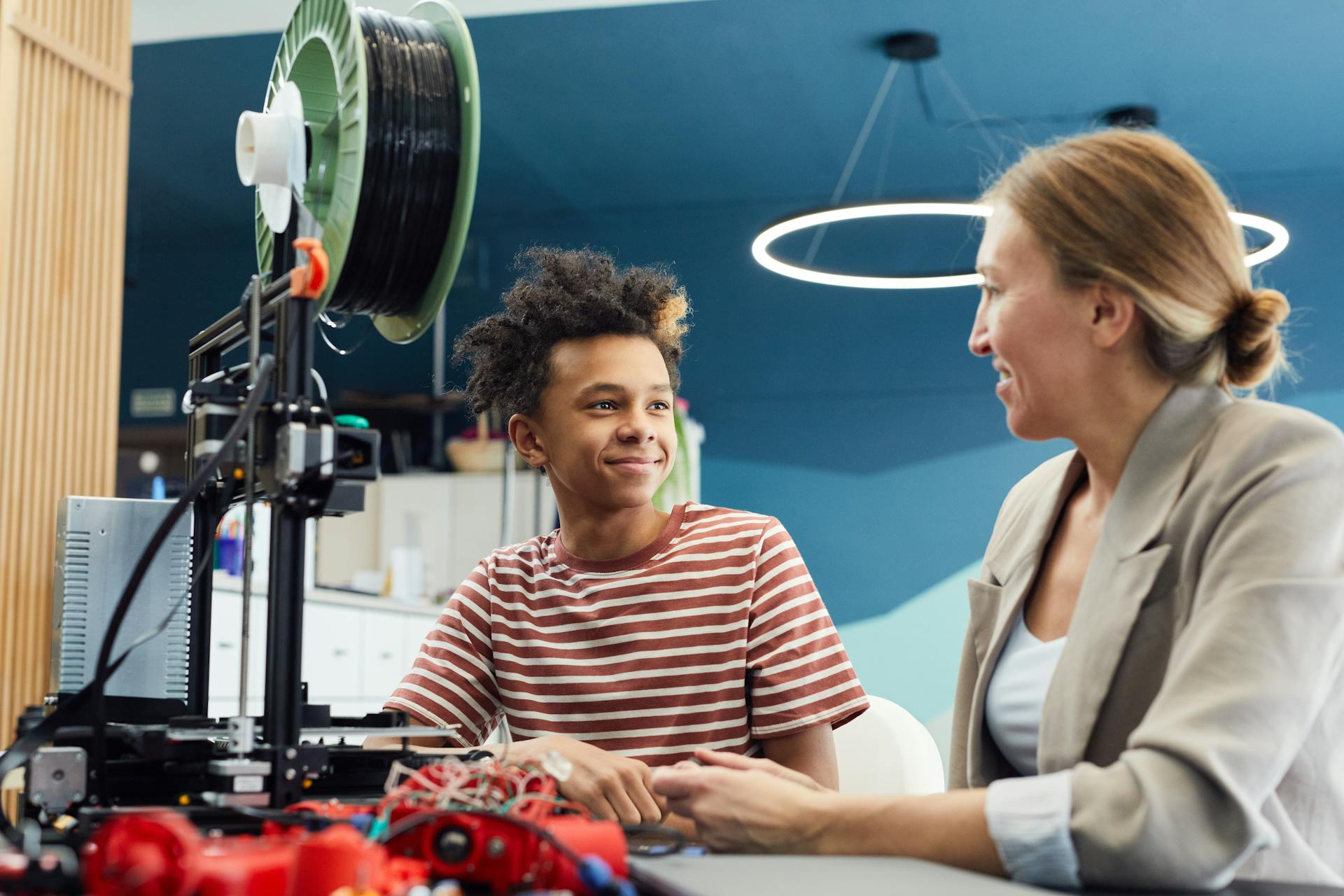 Positive young male engineer sitting at table with woman and working together on project in light room