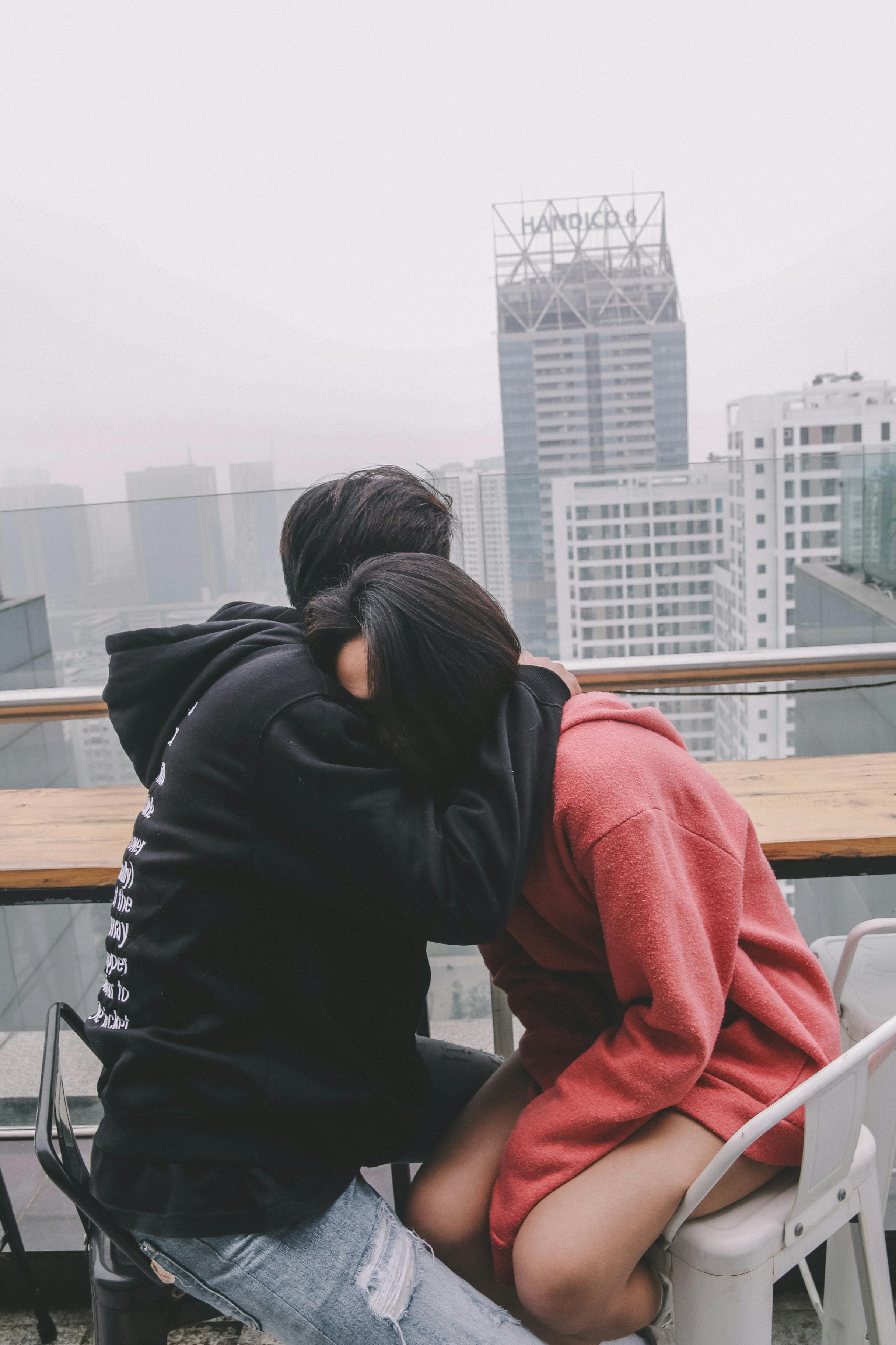 man hugging woman sitting on chair