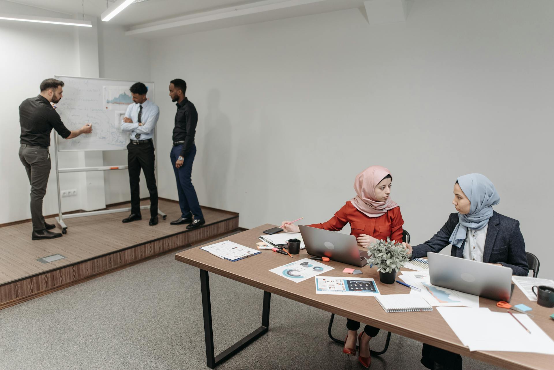 A group of professionals engaging in a team meeting, discussing strategies with laptops and documents.