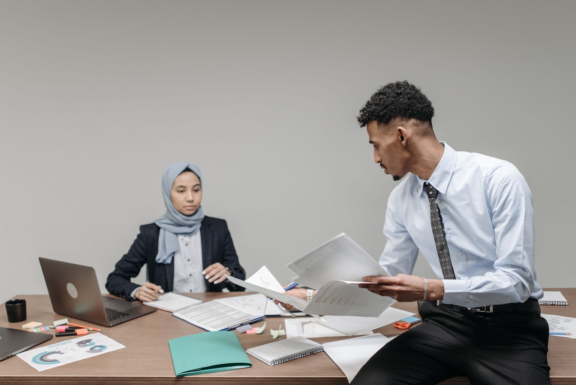 Muslim business professionals collaborating at desk in modern office.